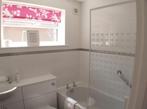 淡水Sunny View, 87 Brambles Chine的带淋浴和浴缸的浴室以及窗户。
