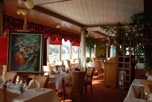 蒙特里夏尔Hôtel Le Bellevue Montrichard 3 étoiles的餐厅设有桌椅,墙上挂有绘画作品