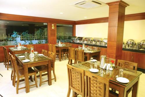 马杜赖米纳克什阳光酒店的一间带木桌椅的餐厅和一间酒吧
