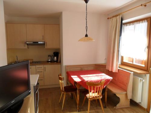 维拉巴萨Appartamenti Stauderhof的厨房配有桌子和红色的桌子及椅子