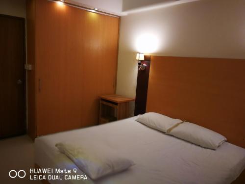 达卡Rajanigandha Family Suites的卧室配有白色的床和木制床头板