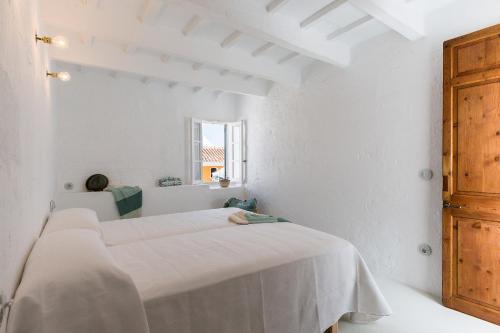 休达德亚Ses Voltes Sant Antoni的白色的客房设有两张床和窗户。