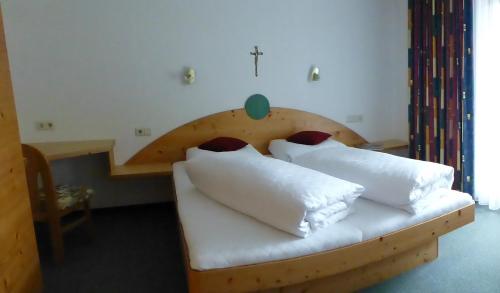 蒂罗尔-泽费尔德盖斯豪斯穆勒-润特纳家庭酒店的一间卧室配有带白色枕头的木床