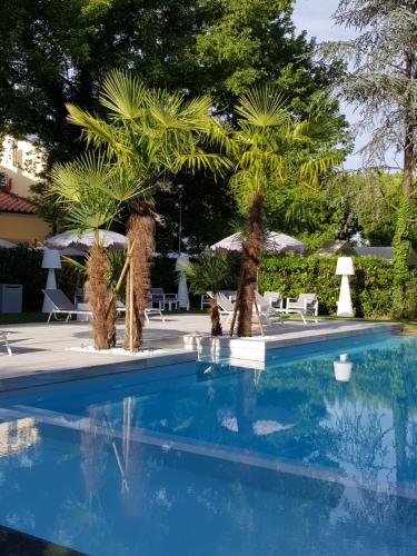 卢卡帮切利别墅公园汉布罗斯酒店的一个带棕榈树和椅子的蓝色游泳池
