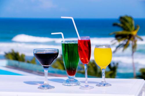 米瑞莎米瑞莎盖特酒店的坐在靠近海洋的桌子上,放着三杯酒