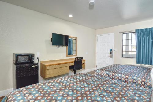 巴顿威洛巴顿威洛北5号州际公路瓦卡班德酒店的一间卧室配有两张床、一张桌子和一台电视。