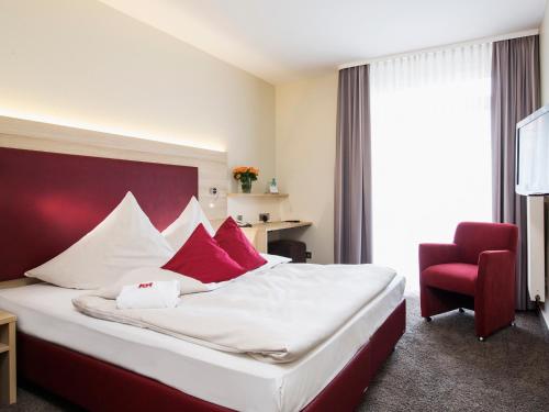 汉诺威莱讷宫康库德酒店的酒店客房,配有一张床和一张红色椅子