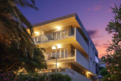 赫瓦尔Pharia Hotel and Apartments - by the beach的白色的建筑,背面有日落