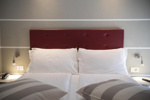加尔达Hotel Imperial ***S的一张带红色床头板和白色枕头的床