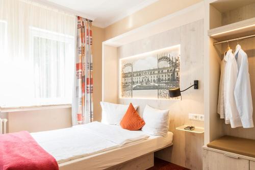 汉诺威伊莉莎白萨加尔尼酒店的一间卧室配有带白色床单和橙色枕头的床。