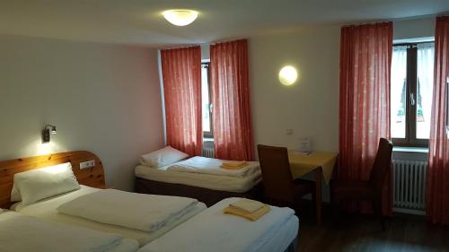 弗莱堡Hotel Gasthaus Rössle的酒店客房设有两张床、一张桌子和窗户。