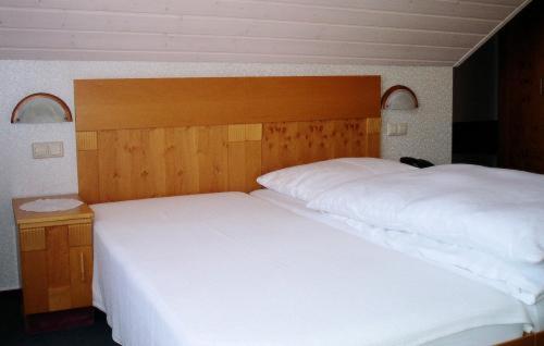 阿尔道夫瓦尔德内尔宾馆的一间卧室配有两张白色的床和木制床头板