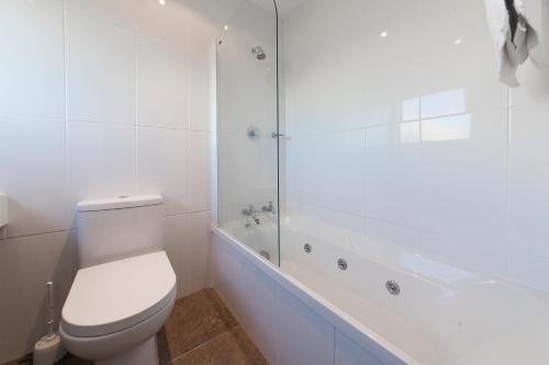 陶波陶波湖区度假酒店的白色的浴室设有卫生间和浴缸。