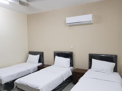塞拉莱Today House Suites的一间设有三张床的房间,墙上装有空调