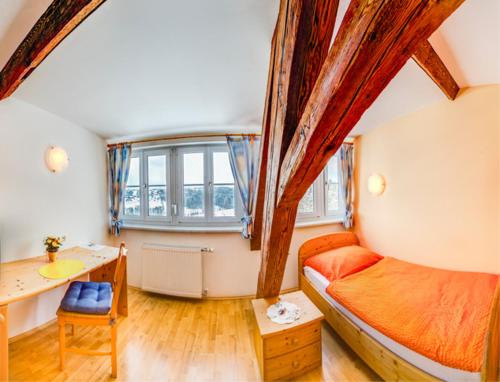 兰纳赫福鲁克斯佩森扎格勒霍夫酒店的一间卧室配有一张床、一张书桌和一个窗户。