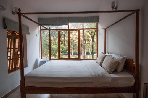 阿斯高Botanique Goa的一间卧室设有一张四柱床和窗户