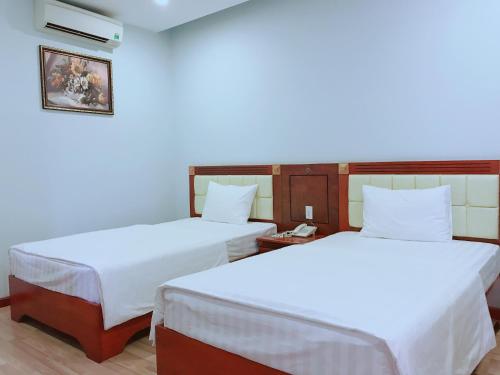 波来古市黄玉酒店的配有白色床单的客房内的两张床
