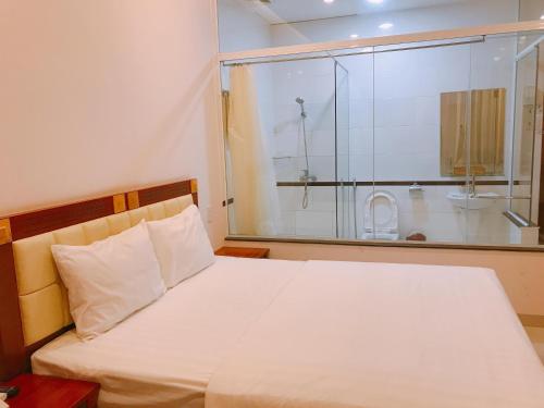 波来古市黄玉酒店的一间卧室设有一张床和一个玻璃淋浴间