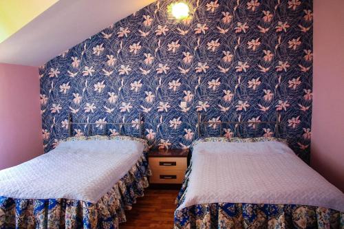 乔尔蓬阿塔Osobyi Guest house的一张带花卉壁纸的客房内的两张床