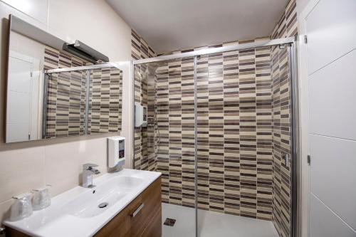 拉赫Apartamentos VIDA Mar de Laxe的一间带水槽和玻璃淋浴的浴室
