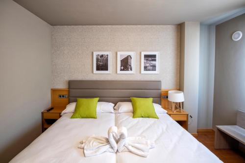 拉赫Hotel VIDA Mar de Laxe的卧室配有带绿色枕头的大型白色床