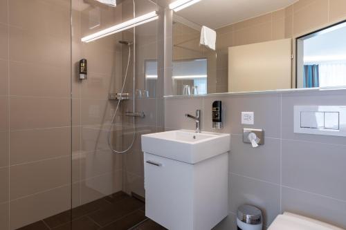 苏黎世苏黎世之旅酒店的白色的浴室设有水槽和淋浴。
