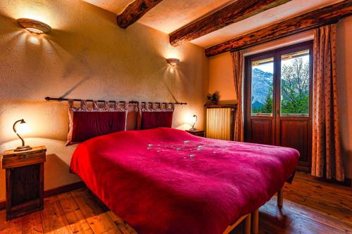 切萨纳·都灵尼斯Agriturismo il Fiocco的一间卧室设有一张红色大床和窗户