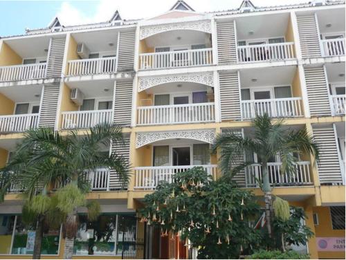 圣丹尼斯Hotel-appart Les Manguiers的一座白色的大建筑,前面有棕榈树