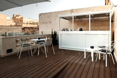 瓦莱塔帕莱斯勒布伦酒店的铺有木地板,设有带桌椅的阳台。