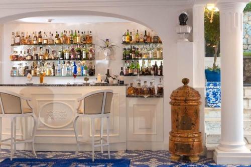卡普里卡萨莫格诺酒店的酒吧设有两把椅子和一个带饮料的吧台