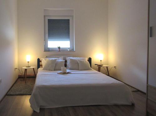 奥西耶克Apartment & Room Renee的一间卧室配有一张带两盏灯的大型白色床。