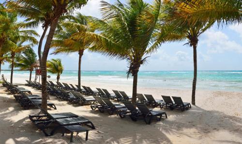 西普哈加泰罗尼亚皇家图卢姆海滩Spa度假村 - 仅限成人 - 全包的棕榈树海滩上的一排椅子