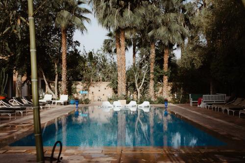 马拉喀什布莱德农家乐的一个带白色椅子和棕榈树的游泳池