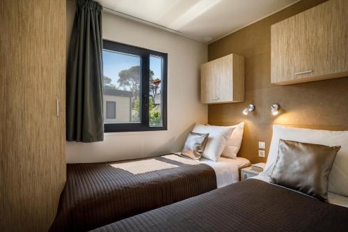拉布Padova Premium Camping Resort by Valamar的酒店客房设有两张床和窗户。