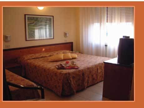 里米尼莫德尔诺酒店的一间卧室配有一张带电视和桌子的床。