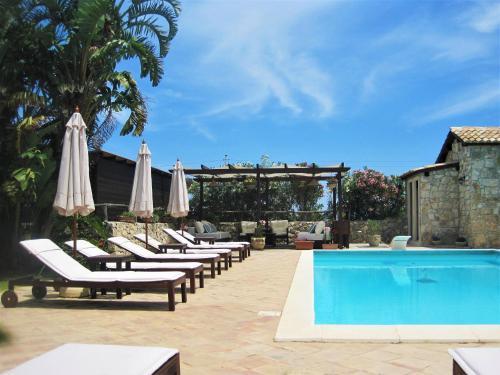 锡拉库扎B&B Villa Giusy的一把带遮阳伞和游泳池的躺椅