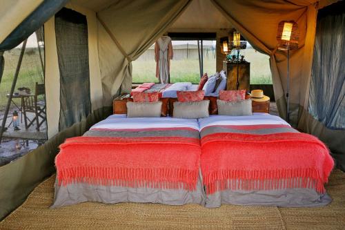 巴纳吉Pumzika Luxury Safari Camp的红色枕头帐篷内的一张床位