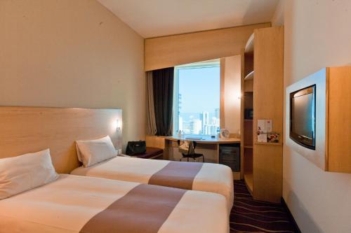 科威特ibis Sharq的酒店客房设有两张床、一张桌子和一台电视。