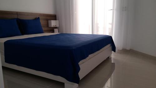 甘达坞伊港appart luxueux pieds dans l'eau的一间卧室配有一张带蓝色床单的床和一扇窗户。