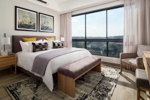 比勒陀利亚The Regency Apartment Hotel Menlyn的一间卧室设有一张大床和一个大窗户