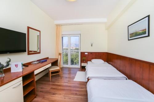 Opuzen梅洛特酒店的一间医院间,配有两张床和一张书桌