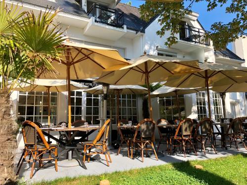 拉波勒Hôtel-Restaurant La Mascotte的户外用餐区配有桌椅和遮阳伞。