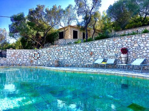 Porto OziasNereidi Pool Villas的一个带两把椅子和石墙的游泳池