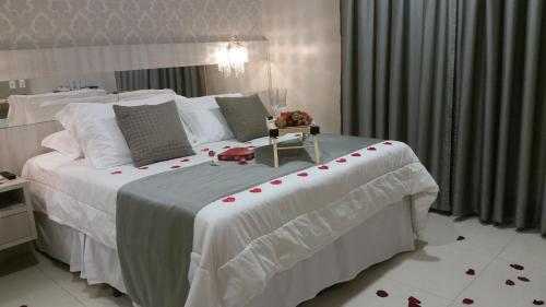 AriquemesValérius Palace Hotel的一间卧室配有一张大白色的红色玫瑰床
