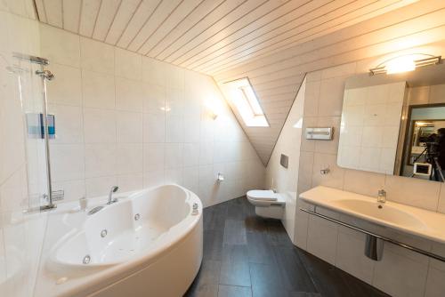 Mühledorf克罗伊茨酒店的带浴缸、盥洗盆和卫生间的浴室