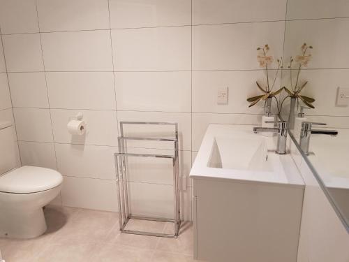 陶朗加Botanical Haven BnB的白色的浴室设有水槽和卫生间。