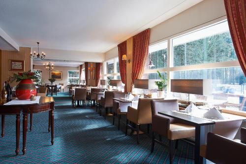 韦斯特博克鲁伊格韦恩酒店-餐厅的餐厅设有桌椅和大窗户。
