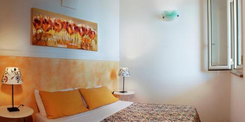 圣凯撒利亚温泉Il Corbezzolo的卧室配有一张床,墙上挂有绘画作品