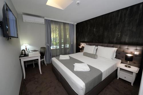 斯科普里Hotel Alexandar II的酒店客房设有一张大床和一张书桌。
