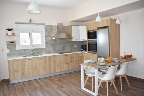 普拉基亚斯Sun & Sea Apartments Plakias的一间带桌椅的厨房和一间带白色橱柜的厨房